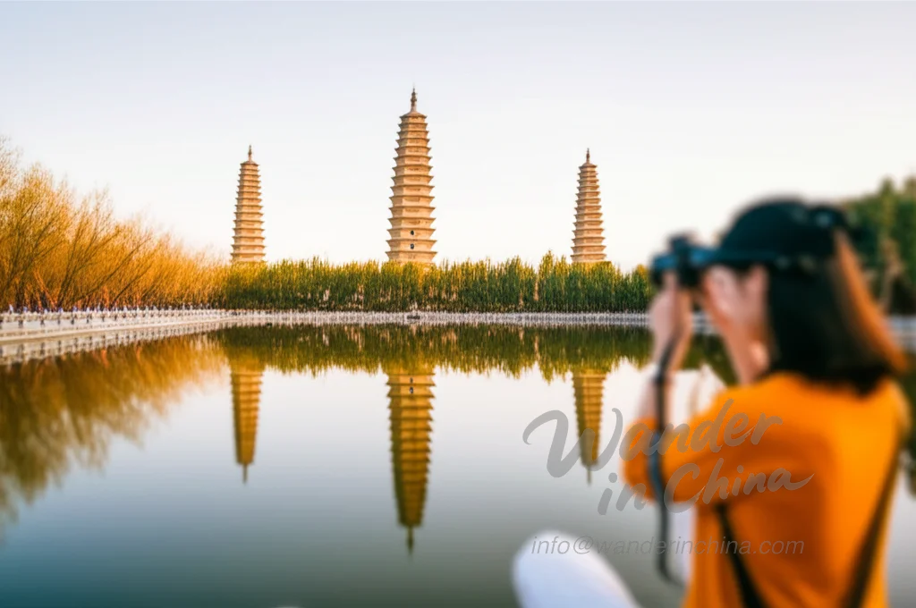 観光客が写真を撮っている反射池に映る大理三塔。