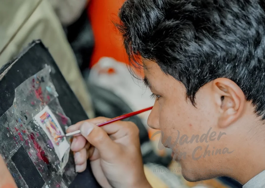 Artisan tibétain confectionnant une peinture thangka.