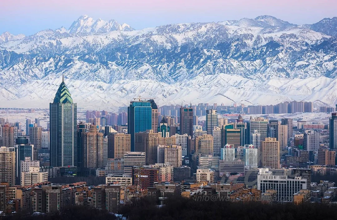 Urumqi skyline at sunset with Tian Shan mountains.
